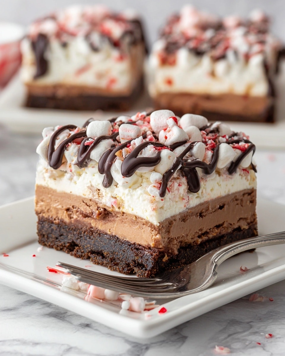 A square layered dessert bar is shown on a white square plate placed on a white marbled surface. The bar has five layers: the bottom layer is a dark brown, crumbly cookie crust; above it is a light brown creamy layer; then a thick dark brown chocolate mousse layer with small white pieces inside; on top of that is a fluffy white layer with mini marshmallows and crushed red and white peppermint bits; the very top has dark chocolate drizzle zigzagging across. A silver fork is cutting into the front corner of the bar. In the blurred background, another full bar piece is visible. Photo taken with an iphone --ar 4:5 --v 7