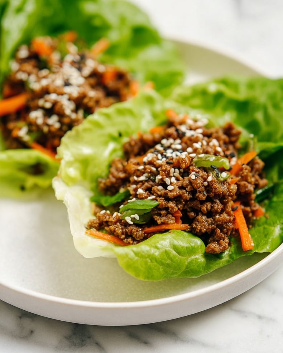 Two lettuce cups sit on a white plate with a white marbled surface below. Each cup has a bright green, crisp lettuce leaf folded like a bowl. Inside the leaf, there is a layer of cooked ground meat mixed with small pieces of orange carrot and green vegetables. The meat mixture is topped with white and black sesame seeds evenly spread across the surface. The textures show a contrast between the soft lettuce and the crumbly, juicy meat. Photo taken with an iphone --ar 4:5 --v 7