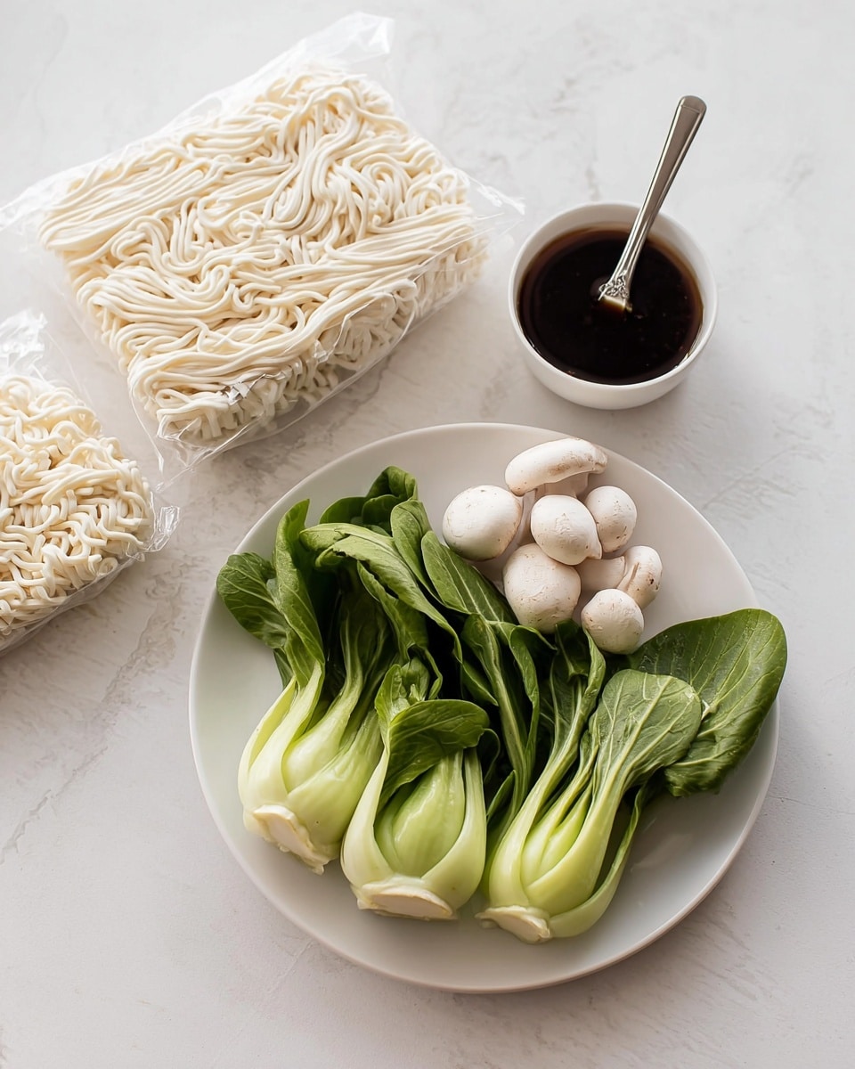 A white plate holds three green baby bok choy with smooth stalks and broad leafy tops, along with five small white mushrooms with round caps placed in front of the bok choy. To the left on a white marbled surface are three vacuum-sealed blocks of thick white noodles stacked slightly overlapping each other. Above the noodles is a white bowl containing dark soy sauce with a silver fork resting in it, the fork's tines dipped into the sauce. The overall scene is bright and clean with fresh ingredients arranged neatly. photo taken with an iphone --ar 4:5 --v 7