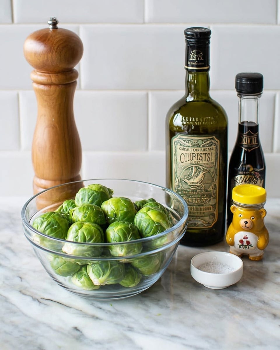 A clear glass bowl filled with fresh, bright green Brussels sprouts sits on a white marbled surface. To the left of the bowl is a tall wooden pepper grinder with a smooth finish. Behind the bowl in the center is a dark green bottle of extra virgin olive oil with an old-fashioned label. To the right of the olive oil is a smaller clear glass bottle of dark balsamic vinegar with a black cap and a vintage label. Further right is a small white dish holding coarse salt, and next to it is a small honey container shaped like a bear with a yellow lid. The background is a simple white tiled wall. Photo taken with an iphone --ar 4:5 --v 7