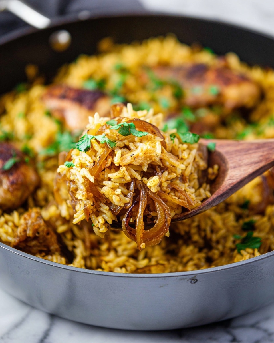 A close-up view of a grey pan filled with seasoned cooked rice with a yellow tint mixed with caramelized brown onion slices, showing pieces of browned chicken with green parsley leaves on top. A wooden spoon lifts a portion of the rice and onions from the pan, highlighting the texture of the fluffy rice and soft onions. The background is softly blurred, emphasizing the food in the pan, which sits on a white marbled surface photo taken with an iphone --ar 4:5 --v 7