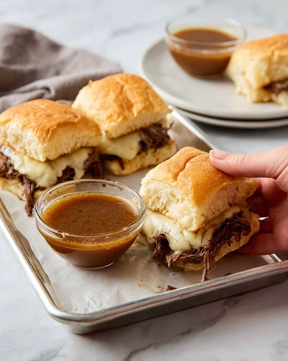 The image shows three small square sandwiches on a metal tray with white parchment paper. Each sandwich has a soft, golden-brown top bun, a middle layer of melted cheese with a smooth, creamy texture, and a bottom layer of dark shredded meat. In front of the sandwiches, there is a small clear glass bowl full of brown dipping sauce with a slightly oily surface. A woman's hand holds the sandwich closest to the camera, positioned above the sauce. In the background, there is a white plate with another small glass bowl of dipping sauce, all on a white marbled surface. Photo taken with an iphone --ar 4:5 --v 7