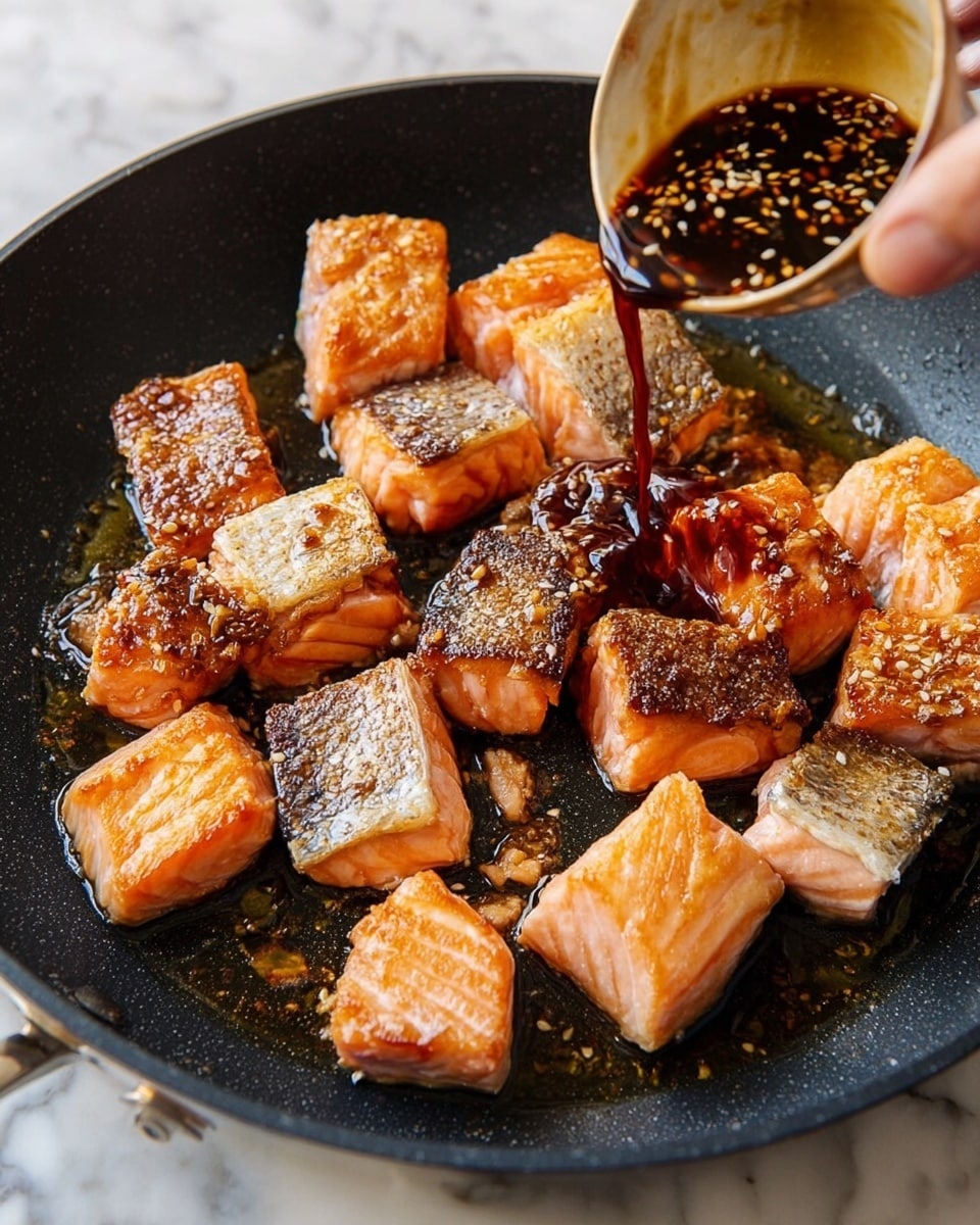 In a black pan on a white marbled surface, there are many small salmon pieces with crispy golden-brown skin on top and pinkish flesh at the bottom, arranged unevenly in the pan. A woman's hand is pouring a dark brown sauce with visible sesame seeds over the salmon, creating a glossy effect on the fish. The pan shows some oil shining between the pieces, highlighting their cooked texture. Photo taken with an iphone --ar 4:5 --v 7