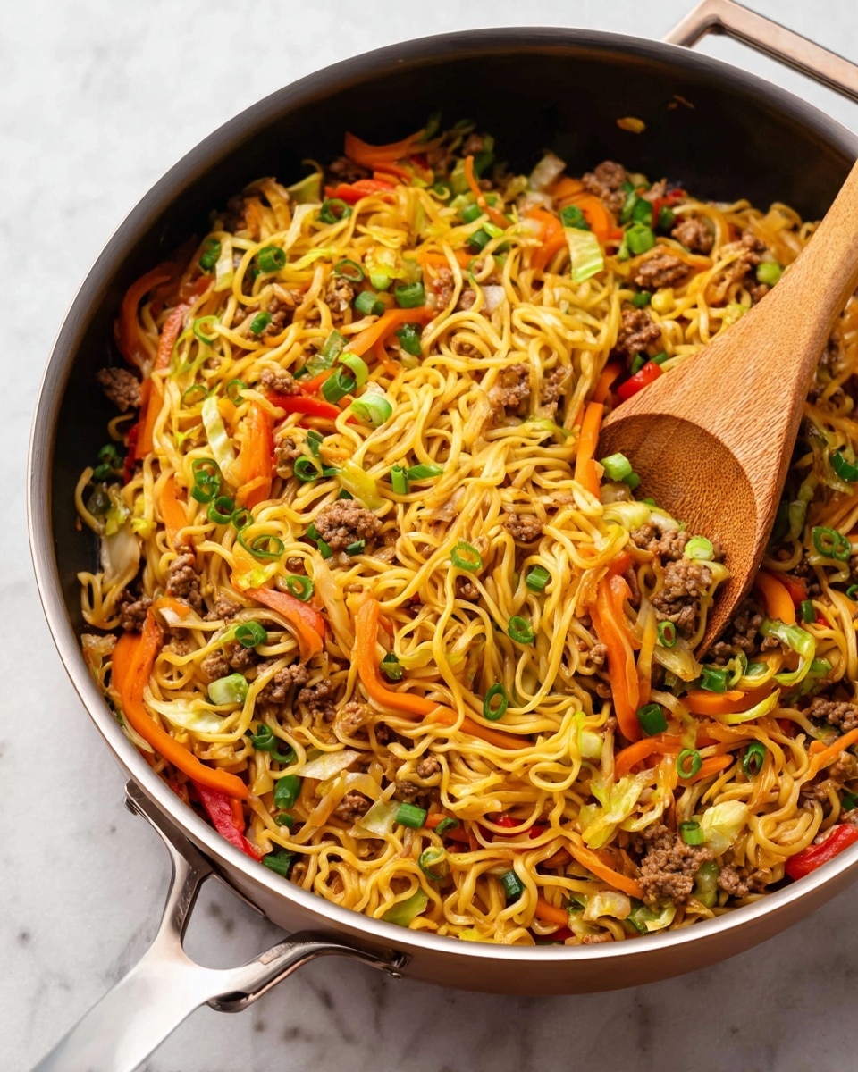 A large pan filled with cooked yellow noodles mixed with small pieces of browned meat, thin strips of orange carrots, red and yellow bell pepper slices, and bits of light green cabbage. The top is sprinkled with chopped green onions, adding a fresh touch. A wooden spoon is inside the pan, resting on the noodles and vegetables. The pan is placed on a white marbled surface. photo taken with an iphone --ar 4:5 --v 7