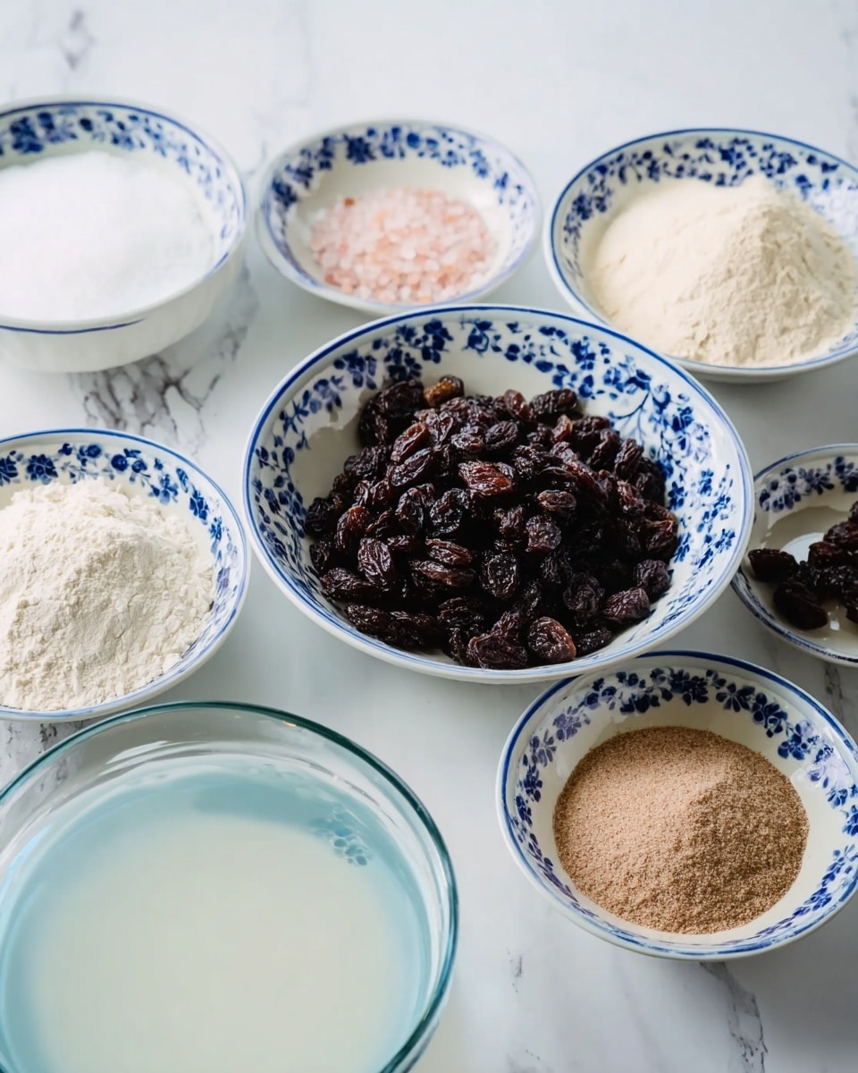 The image shows several small white bowls with blue floral patterns arranged on a white marbled textured surface. One medium bowl in the center is filled with dark brown raisins that have a wrinkled texture. Surrounding it are five smaller bowls: one with white flour, one with light beige granulated sugar, one with pink Himalayan salt, one with a light brown, fine powder, and another with a white liquid that looks like milk or cream. Additionally, there is one clear glass bowl with water visible on the bottom left side. photo taken with an iphone --ar 4:5 --v 7