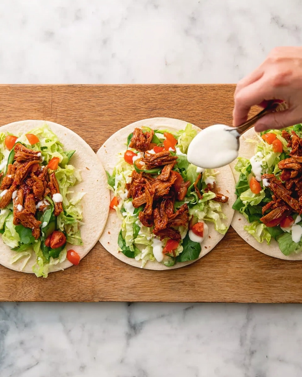 Three white small tortillas are placed on a wooden board which is on a white marbled surface. Each tortilla has a base layer of shredded green lettuce mixed with small red tomato pieces. On top of the vegetables, there are several pieces of cooked reddish-brown meat strips. On one tortilla, a woman's hand is holding a spoon with white sauce, ready to spread it on the meat. The colors of the ingredients are bright and vibrant with fresh textures visible. Photo taken with an iphone --ar 4:5 --v 7