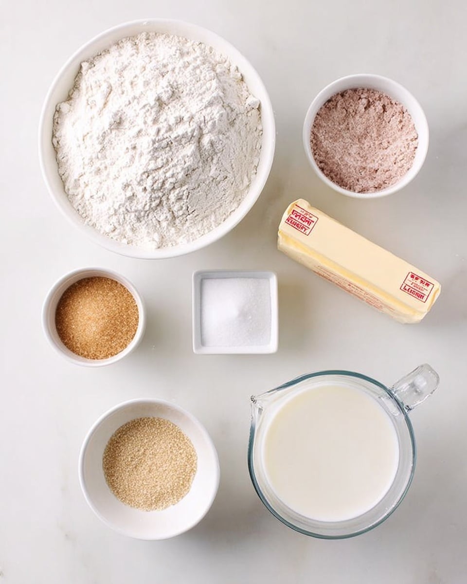 The image shows an overhead view of several ingredients arranged neatly on a white marbled surface. In the center is a large white bowl filled with white flour. To its right is a clear glass measuring cup containing white milk. Above the milk is a small white bowl holding a light brown powder. Next to the flour bowl, to its left, is a small white bowl with beige yeast granules. Below the flour is a small white bowl filled with light brown sugar. A stick of butter wrapped in paper with red text is placed next to the brown sugar bowl. There are two more small white containers on the right side, one with white salt and another with a white powder, possibly baking powder or salt. The arrangement is clean and bright, all on the white marbled surface photo taken with an iphone --ar 4:5 --v 7