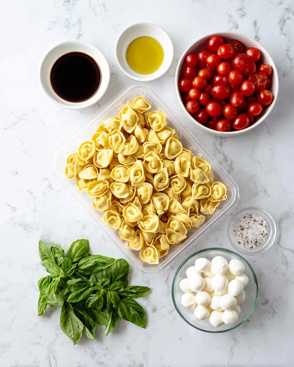 A clear plastic tray filled with a single layer of uncooked yellow tortellini pasta sits near the center on a white marbled surface. To the top left of the tray are two white bowls, one filled with dark brown balsamic vinegar and the other with golden olive oil. To the top right, a white bowl holds many small, bright red cherry tomatoes. Below the tray, fresh green basil leaves lay in a small bunch. To the bottom right, a small clear glass bowl contains white mozzarella balls, and next to it is a small white bowl with a light sprinkling of salt. All items are evenly spaced and arranged neatly. Photo taken with an iphone --ar 4:5 --v 7