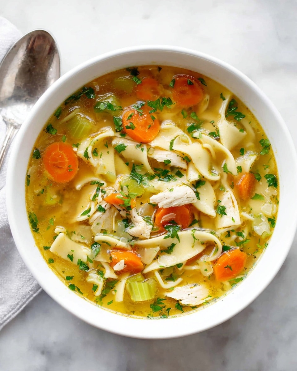 A red cooking pot filled with clear chicken noodle soup showing several layers: the base is a light yellow broth with small green herb pieces scattered throughout, the middle layer has wide, flat white noodles mixed with small orange carrot slices and green celery pieces, while tender white chicken pieces sit on top and are lifted by a black ladle in the center of the image. The pot sits on a white marbled surface, and a bunch of fresh green parsley and an orange carrot are partly visible in the background. photo taken with an iphone --ar 4:5 --v 7