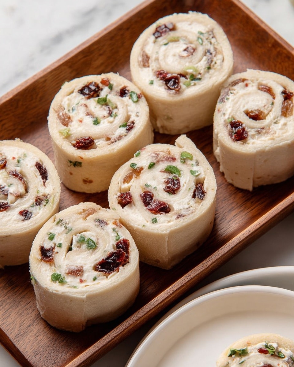 The image shows six small rolls arranged on a wooden tray. Each roll has two main layers: a light beige outer layer that looks soft and slightly toasted with some brown spots, and a creamy white inner layer speckled with pieces of dark red dried fruit and small bits of green herbs. The rolls are thick and round, showcasing a spiral pattern where the inner creamy filling meets the outer wrap. The tray sits on a white marbled surface, and there is a white plate partially visible in the lower right corner with a similar roll on it. Photo taken with an iphone --ar 4:5 --v 7