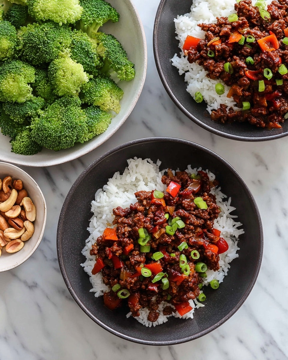The image shows two dark bowls filled with white rice at the bottom layer, topped with a thick layer of cooked ground meat mixed with small chunks of red bell pepper and onion. The meat layer is dark brown with a shiny texture from sauce, and it is sprinkled with small pieces of chopped green onion for garnish. Next to the bowls, there is a white bowl filled with bright green broccoli florets and another bowl with light brown nuts, all placed on a white marbled surface. Photo taken with an iphone --ar 4:5 --v 7