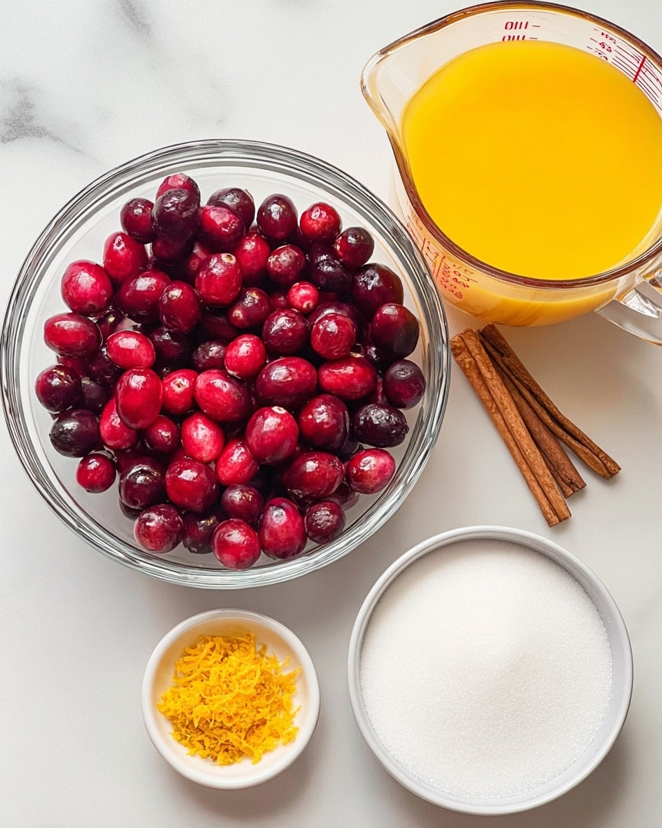A clear glass bowl filled with fresh red and dark red cranberries sits on a white marbled surface. To the right of the bowl is a clear glass measuring jug filled with bright orange juice. Below the bowl of cranberries, there is a clear glass bowl containing white sugar. To the left, two small white bowls are placed; one holds orange zest, and the other holds a single cinnamon stick. The overall setup is clean, simple, and colorful, with each ingredient clearly visible. photo taken with an iphone --ar 4:5 --v 7