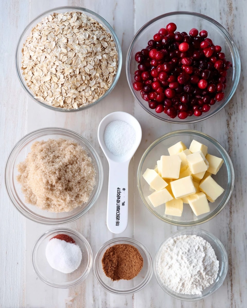 The image shows eight clear glass bowls arranged on a white marbled surface. The top left bowl holds light beige rolled oats with a coarse texture. To the right, a white measuring cup with black measurement marks is filled with bright red and dark red fresh cranberries. Below the oats, a bowl contains light brown sugar with a slightly clumped texture. Next to the sugar, there's a bowl filled with white flour, appearing soft and powdery. At the bottom right, a bowl is filled with small cubes of pale yellow butter. Three smaller bowls hold different powders: one has a medium brown spice, another contains white coarse salt, and the last one has white baking powder or baking soda with a fine texture. The bowls are neatly placed, and the setting is bright and clean with natural light. Photo taken with an iphone --ar 4:5 --v 7