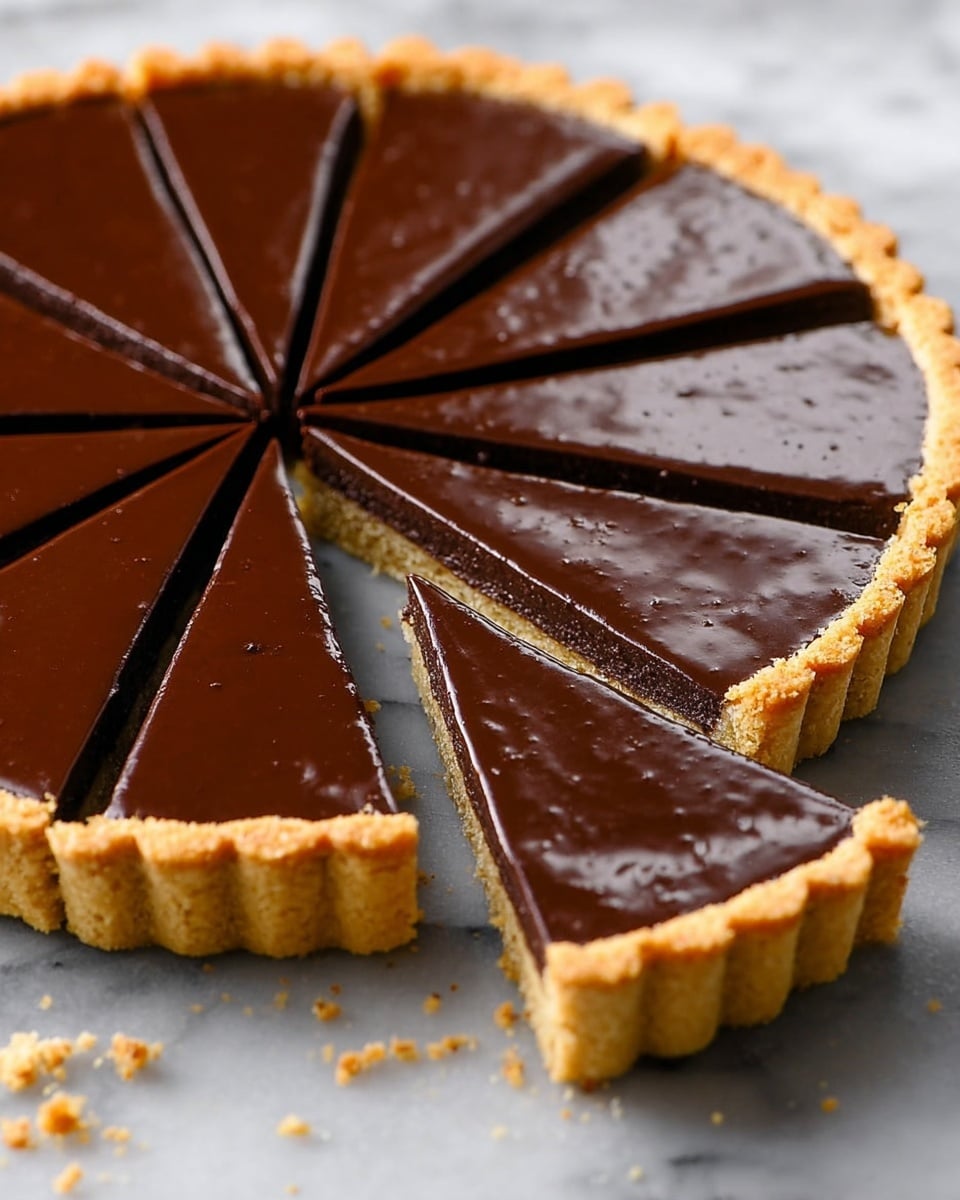 The image shows a round tart cut into ten slices, with one slice slightly pulled out, revealing a three-layer structure. The bottom layer is a golden brown thick crust with a firm, crumbly texture and scalloped edges all around. The middle layer is thin, dark chocolate filling, smooth and glossy, while the top layer is a shiny, rich chocolate ganache with a glassy surface that reflects light. The tart is placed on a white marbled surface, with small crumbs scattered near the crust. Photo taken with an iphone --ar 4:5 --v 7