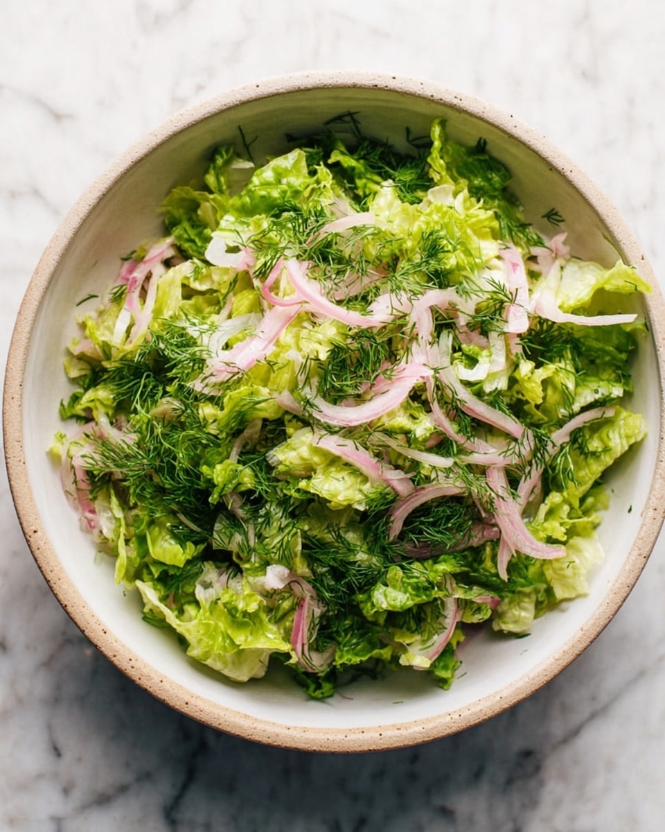 Inside a large shiny metal bowl on a white marbled surface, there is a mix of fresh salad ingredients layered in sections. The base layer consists of torn light green leafy lettuce covering most of the bowl. On top, there are four visible piles: bright green chopped chives at the bottom right, dark green shredded dill at the middle left, a mound of pale pink pickled onions near the top center, and more lettuce filling in gaps around the edges. A woman's hand is pouring a light, creamy dressing from a glass jar onto the salad. The scene is well-lit, showing the freshness of the ingredients clearly. photo taken with an iphone --ar 4:5 --v 7