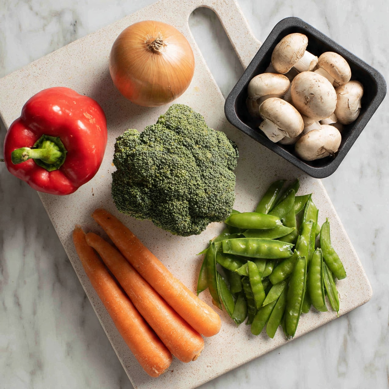 A white cutting board rests on a white marbled surface, holding six fresh vegetables. On the top left is a bright red bell pepper with a shiny smooth surface. Below it, a round brown onion with a dry outer skin sits next to two long, smooth orange carrots placed side by side at the bottom. In the center, there is a large green broccoli head with a dense cluster of tiny buds and thick stalks. On the right, a pile of vibrant green snap peas with smooth shells is spread loosely. Above the snap peas, a black container holds several round, light brown mushrooms with slightly textured caps. Photo taken with an iphone --ar 4:5 --v 7