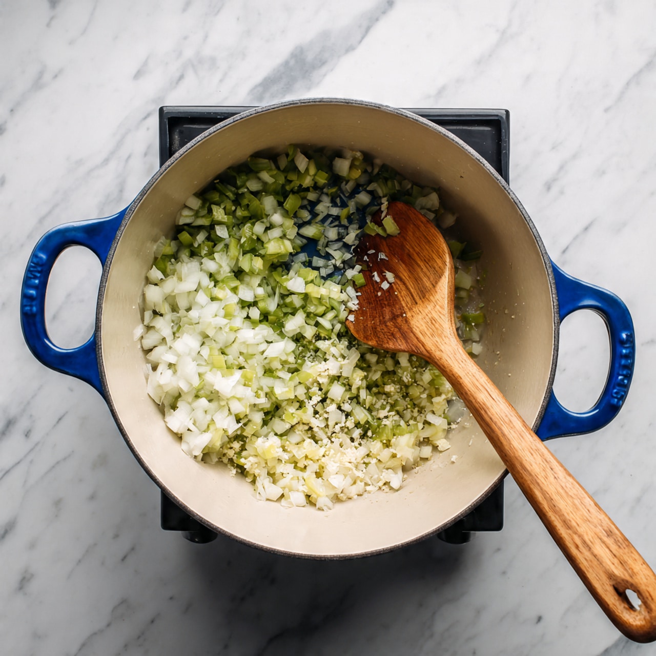 A blue pot with cream inside is on a black stove with a white marbled surface beside it. Inside the pot, there are two layers of vegetables: a bottom layer of small chopped green pieces and a top layer of small white onion pieces. A wooden spoon with a long handle is resting diagonally inside the pot, the handle sticking out to the right. photo taken with an iphone --ar 4:5 --v 7