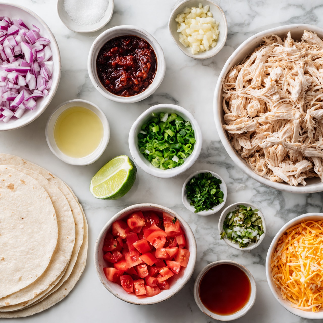 The image shows a flat lay of multiple small white bowls arranged neatly on a white marbled surface, each holding different taco ingredients. From top left, there is a bowl of chopped red onions, next to it a bowl with a dark red chunky sauce, and above it a small bowl with minced garlic. To the right, there’s a small bowl with a reddish liquid sauce, and a large bowl filled with shredded light beige chicken. Below the chicken is a small bowl with a light yellow liquid, likely oil. In the center are three small bowls containing chopped green onions, finely chopped green herbs, and salt. Below those are two larger bowls, one with bright red chopped tomatoes and one with shredded orange cheddar cheese. On the left side at the bottom is a stack of white tortillas. A halved lime is placed near the center of the setup. The overall scene is bright and clean, focused on fresh taco ingredients. Photo taken with an iphone --ar 4:5 --v 7