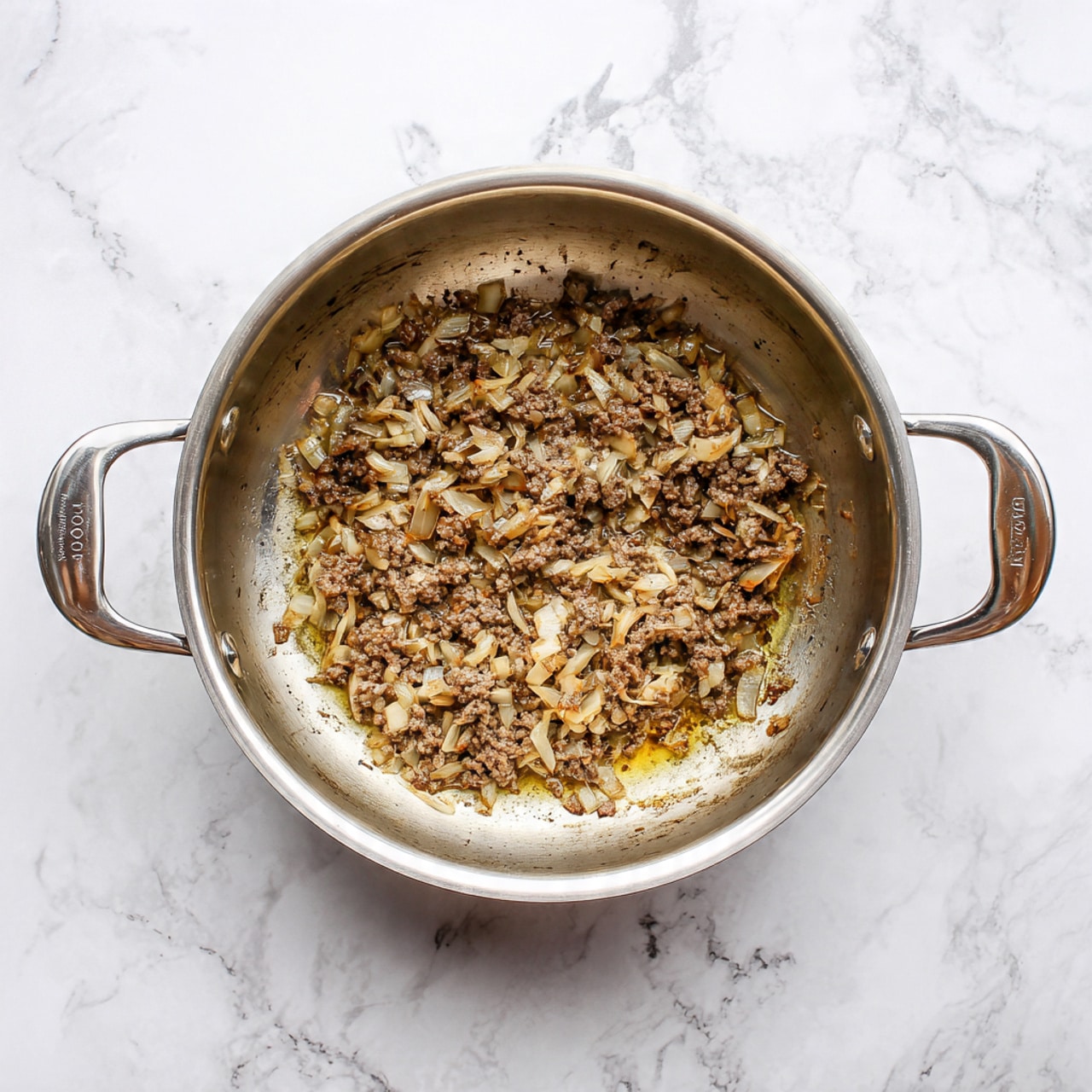 The image shows a silver pot with two handles on a white marbled surface, filled with cooked chopped onions and small pieces of brown minced meat mixed together. The ingredients form a single layer covering the bottom of the pot, showing a texture of soft, cooked onions with a light golden color and tender browned meat bits scattered throughout. The inside of the pot has some shiny oil residue, enhancing the cooked look of the mixture. photo taken with an iphone --ar 4:5 --v 7