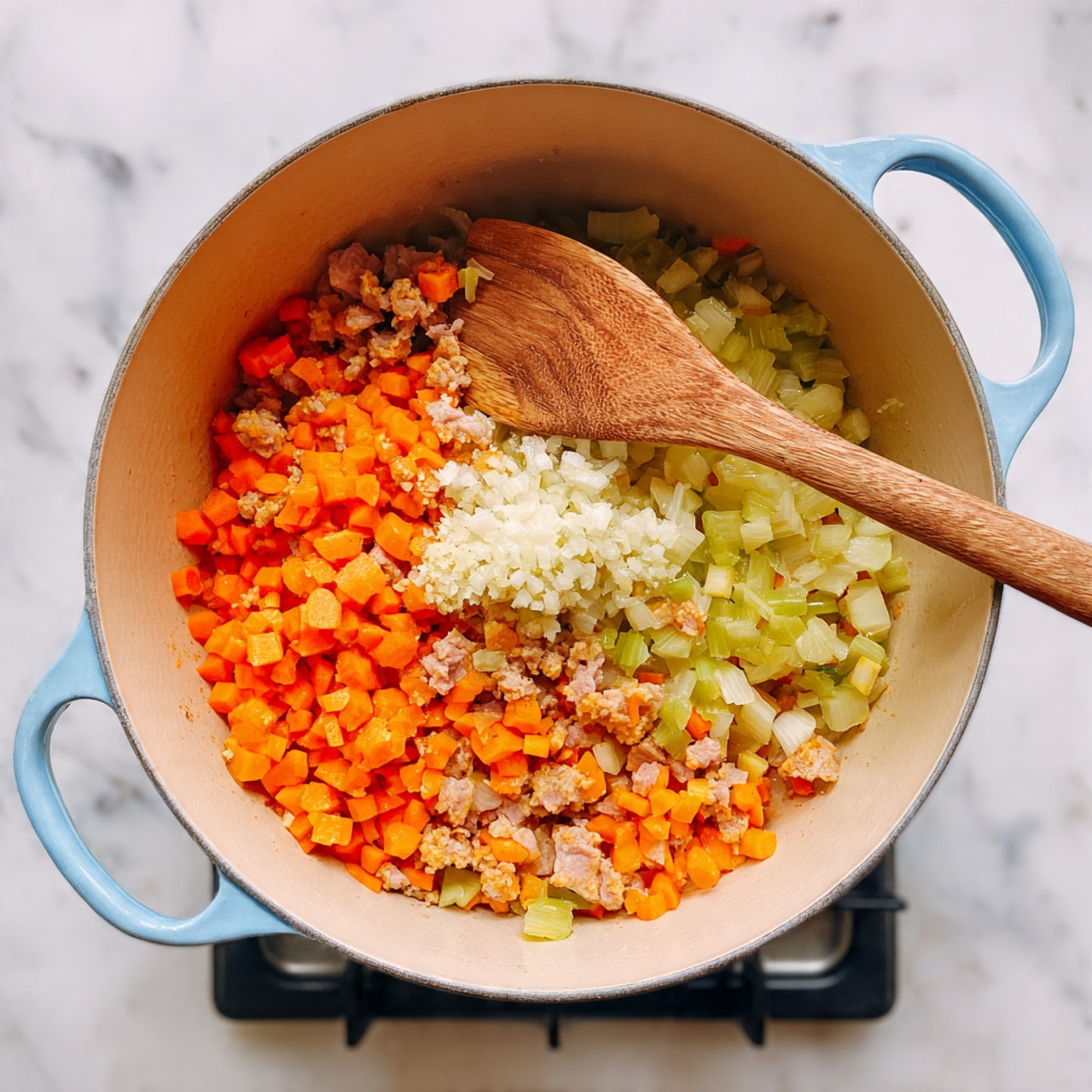 A light blue pot filled with three layers of cooked ingredients is shown on a stove. The bottom layer consists of finely chopped orange carrots, light green celery, and small pieces of white onion. The middle layer has diced pink ham mixed with the vegetables. The top layer shows a small mound of finely chopped white garlic being stirred by a large wooden spoon resting inside the pot. The pot sits on a stove with black grates and the surrounding surface is a white marbled texture. Photo taken with an iphone --ar 4:5 --v 7
