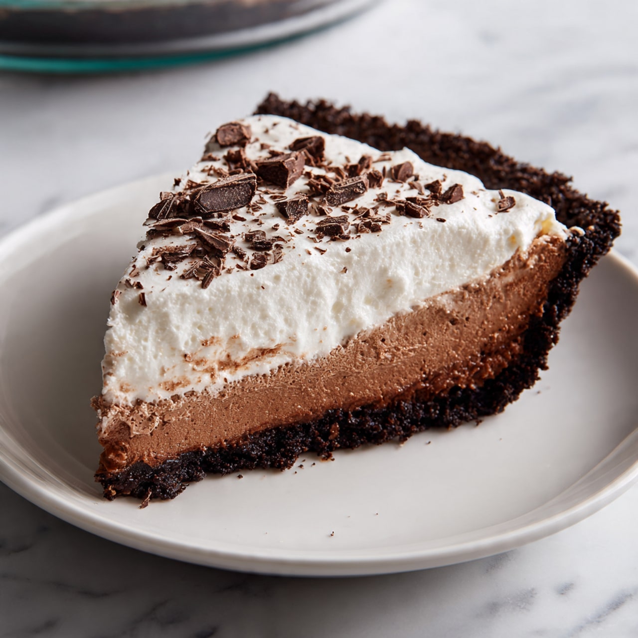 A slice of layered chocolate pie sits on a white plate with a white marbled surface underneath. The bottom layer is dark brown, thick, and dense, like a brownie. Above it is a smooth medium-dark brown chocolate layer, creamy and rich. The next layer is light, fluffy white cream spread evenly on the top. Small bits of chocolate crumb garnish cover the cream layer, adding texture. In front, a spoon holds a bite showing all three layers clearly, with the creamy white layer on top, the chocolate middle layer, and the dark brownie base. Photo taken with an iphone --ar 4:5 --v 7