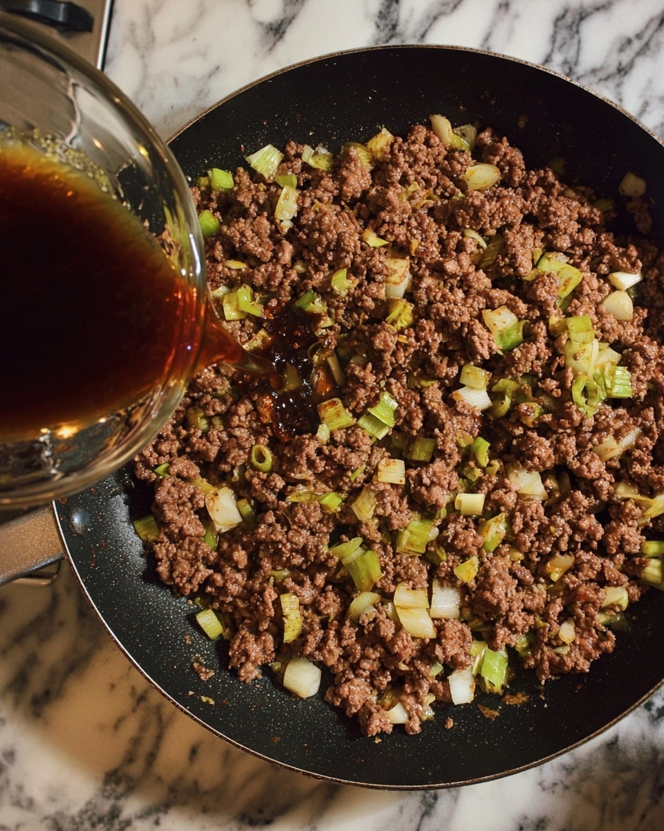 A black frying pan filled with browned ground meat mixed with small pieces of light green and white chopped onions. A glass bowl is tilted near the top left corner, pouring a dark brown liquid sauce over the meat, creating a glossy surface on some parts. The pan sits on a stove with a white marbled surface underneath. Photo taken with an iphone --ar 4:5 --v 7