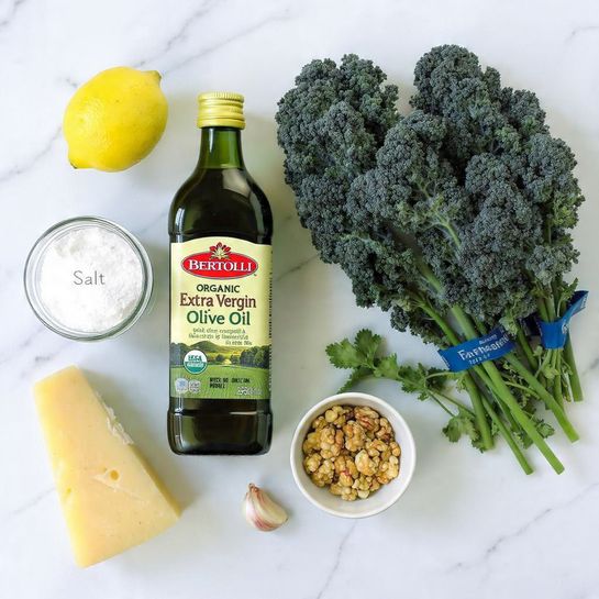 The image shows several fresh ingredients laid out on a white marbled surface. There is a whole lemon with bright yellow skin near the top left. A clear glass jar labeled