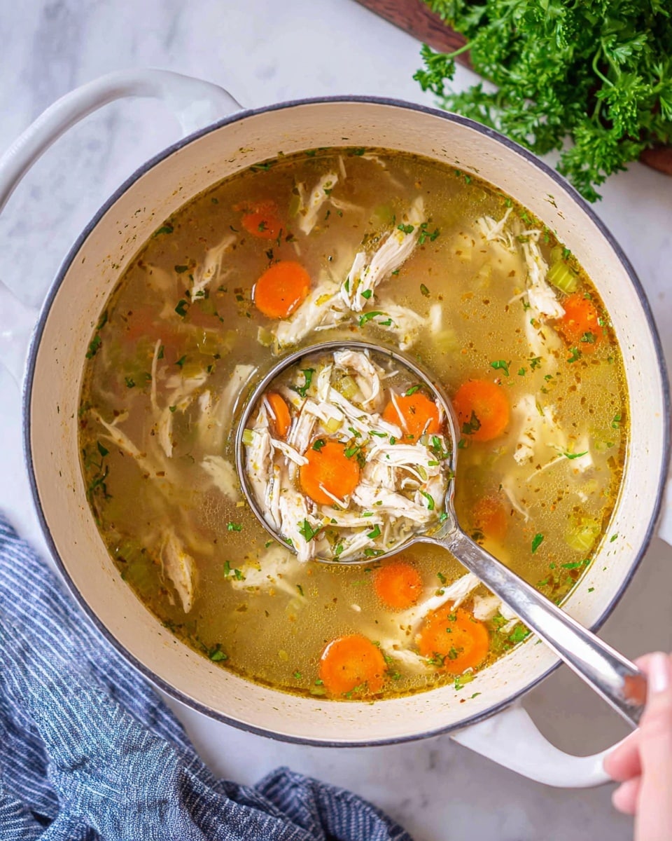 A white bowl filled with a clear broth soup containing several visible layers: the bottom layer has soft shredded chicken pieces in light beige color, mixed with pale white rice grains; above that, there are bright orange round carrot slices and light green celery pieces spread evenly throughout; some small bits of white onion are scattered along with green parsley flakes on top, giving it a fresh look. A silver spoon is placed inside the bowl on the right side. The bowl sits on a white marbled surface, with a wooden pepper grinder and some green parsley visible on the side. Photo taken with an iphone --ar 4:5 --v 7