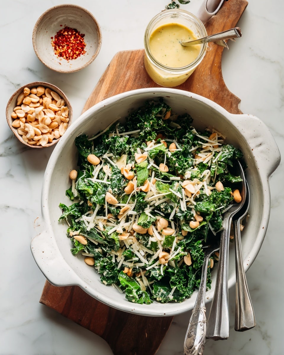 A white bowl with a green leafy salad made of dark kale leaves as the base layer, topped with thin white shreds, scattered light brown peanuts, and fresh green mint leaves placed on top; a bright green lime wedge sits on the right side of the salad. Around the bowl, there is a white marbled surface with small bowls containing coarse white salt, light yellow grated cheese with a chunk, and a jar of thick yellow dressing with a spoon inside. A wooden board holds a small dish with red chili flakes and a lime wedge. Photo taken with an iphone --ar 4:5 --v 7