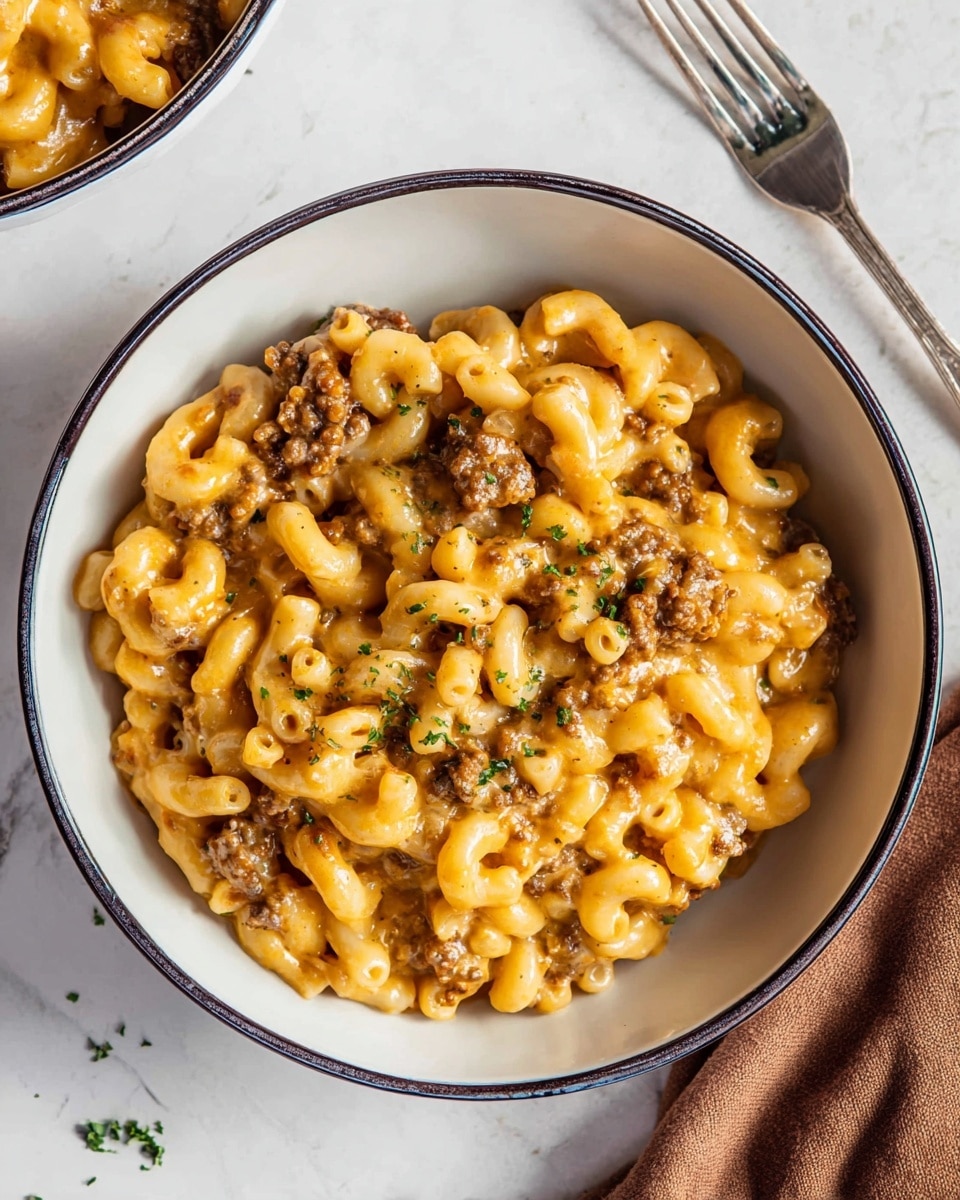 A white bowl with a thin dark rim holds a creamy macaroni dish with soft elbow pasta mixed evenly with small pieces of browned meat and a smooth golden cheese sauce. Tiny green parsley bits are scattered on top, adding a touch of freshness. The bowl sits on a white marbled surface with a soft brown cloth partially visible in the upper right corner and a silver fork resting nearby. In the upper left, part of another bowl with similar food is seen. photo taken with an iphone --ar 4:5 --v 7
