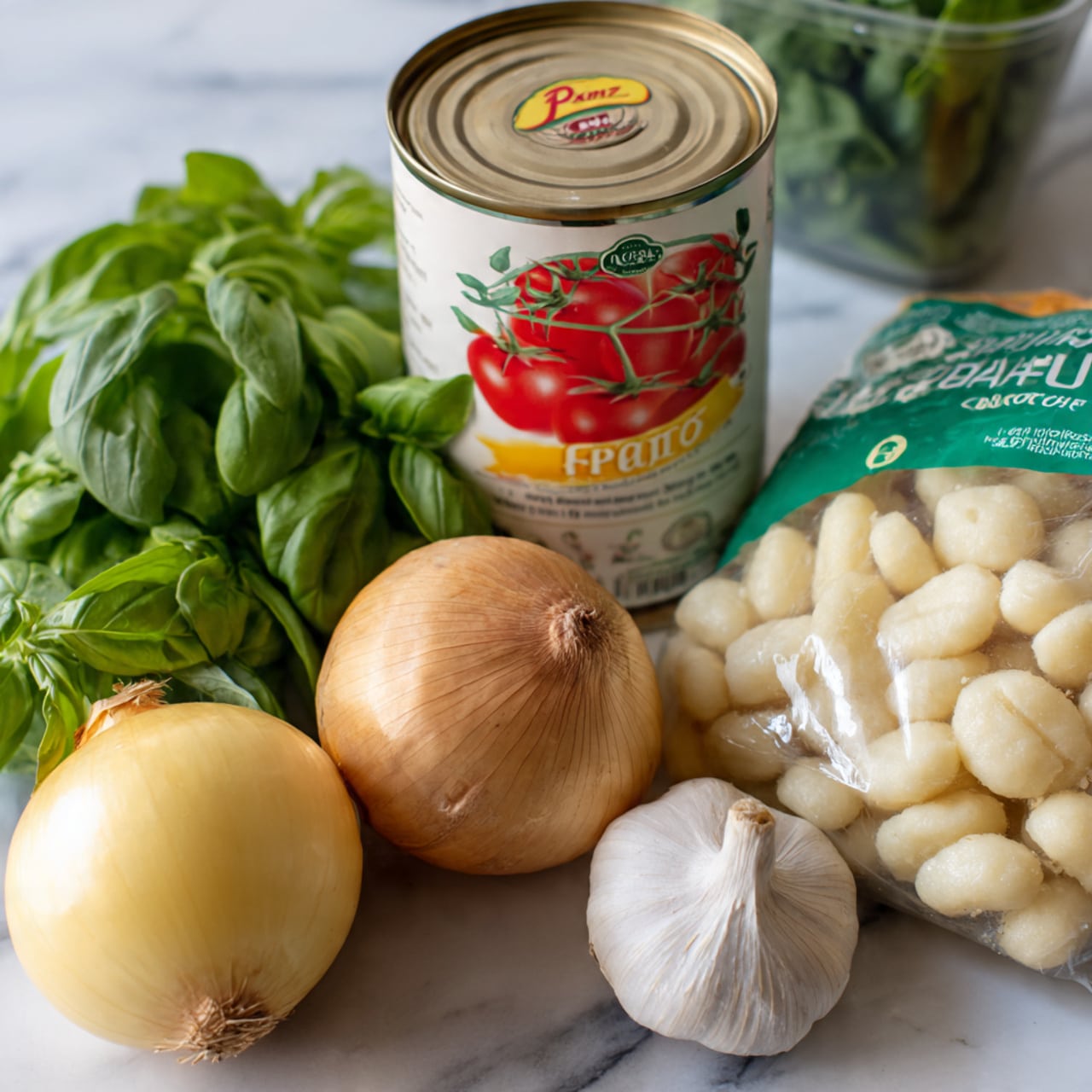 The image shows fresh cooking ingredients placed on a white marbled surface. In the foreground, there is a bunch of bright green basil leaves with smooth and slightly shiny texture. To the left, a whole yellow onion with papery skin and a white garlic bulb with dry, slightly rough outer layers are side by side. Behind them, a large white can with red tomatoes pictured on its label sits upright. To the right, a clear plastic bag with green and white labeling is filled with small, white gnocchi pieces that have soft, rounded shapes. In the far background, a clear container with green spinach leaves is partially visible. photo taken with an iphone --ar 4:5 --v 7