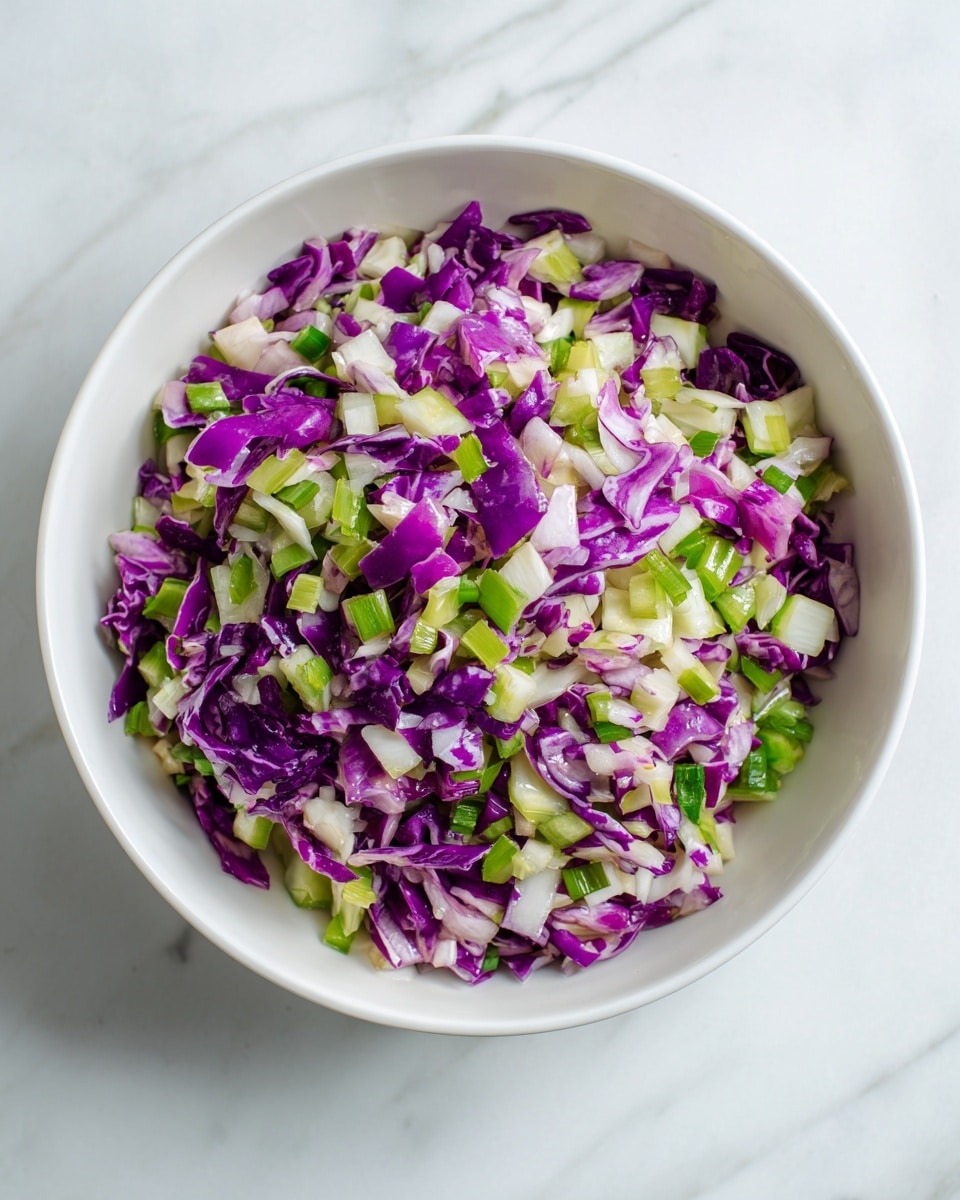 This image shows a white bowl filled with a colorful salad. The salad has three main layers of small pieces mixed together: bright purple cabbage, light green celery, and small bits of white apple or onion. The textures look fresh and crunchy, with the purple cabbage pieces standing out most with their shiny, rough edges. The bowl is set on a white marbled surface that adds a clean and soft background to the vibrant mix inside the bowl. photo taken with an iphone --ar 4:5 --v 7