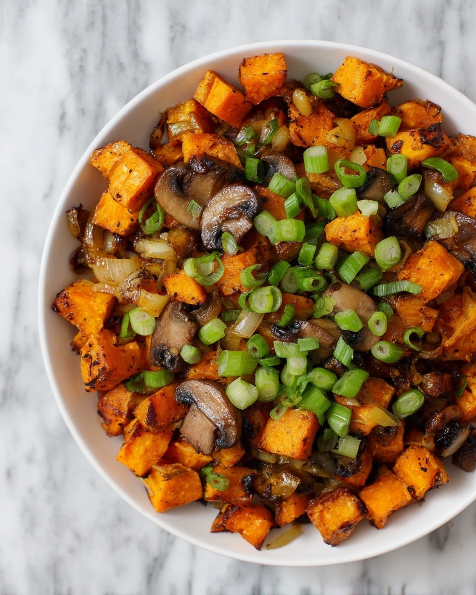 The image shows a close-up of a bowl filled with roasted vegetables. The dish has three main layers: the bottom layer is made up of small, golden-orange roasted sweet potato cubes with slightly charred edges; mixed among the potatoes are small pieces of sautéed mushrooms, which are brown and have a soft texture, and diced onions that are translucent with a reddish tint. The top layer is garnished with fresh, bright green sliced spring onions scattered evenly over the whole dish. The bowl is white and set against a white marbled surface. The photo taken with an iphone --ar 4:5 --v 7