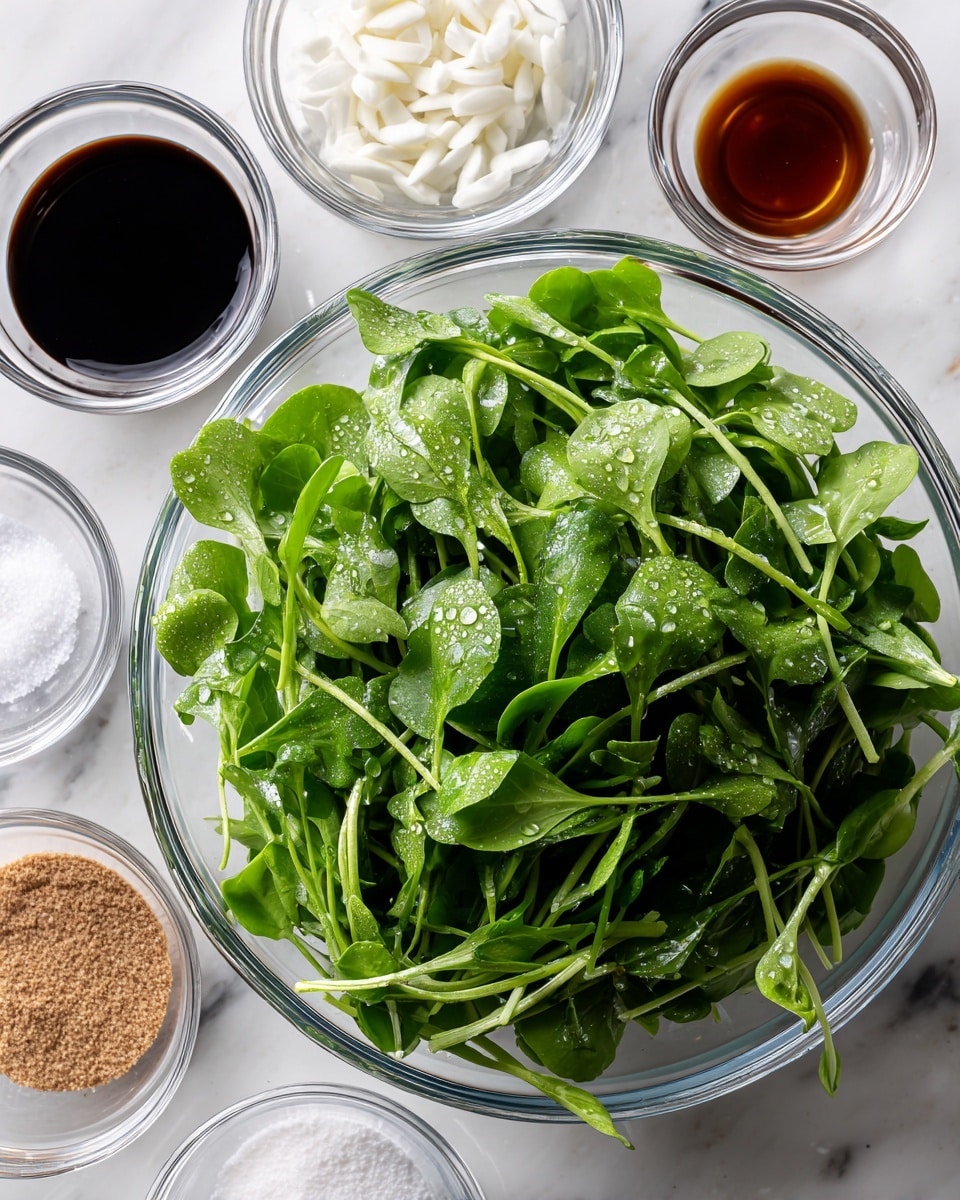 A large clear glass bowl filled with fresh, bright green watercress, with visible stems and leaves showing water droplets. Above it, five small clear glass bowls are arranged in a loose circle on a white marbled surface: one contains dark soy sauce, another holds a thicker dark liquid, one bowl has thin sliced white garlic pieces, another has white granules of salt, and the last one contains a light brown powder. The setup shows clean, fresh ingredients ready for a recipe. Photo taken with an iphone --ar 4:5 --v 7