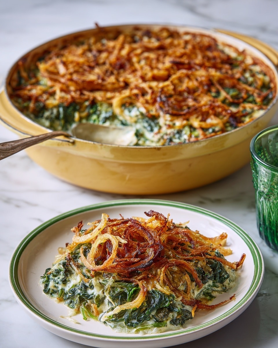 A round yellow pot filled with a layered green and white spinach casserole topped with a crispy, golden brown fried onion layer that has a slightly rough texture. Next to the pot on the left, on a white plate with a green rim, is a serving of the casserole showing the same layers with the green spinach and white creamy base beneath the crunchy onion top. In the background on the right is a green tinted glass and part of a white plate. All items are placed on a white marbled surface. photo taken with an iphone --ar 4:5 --v 7