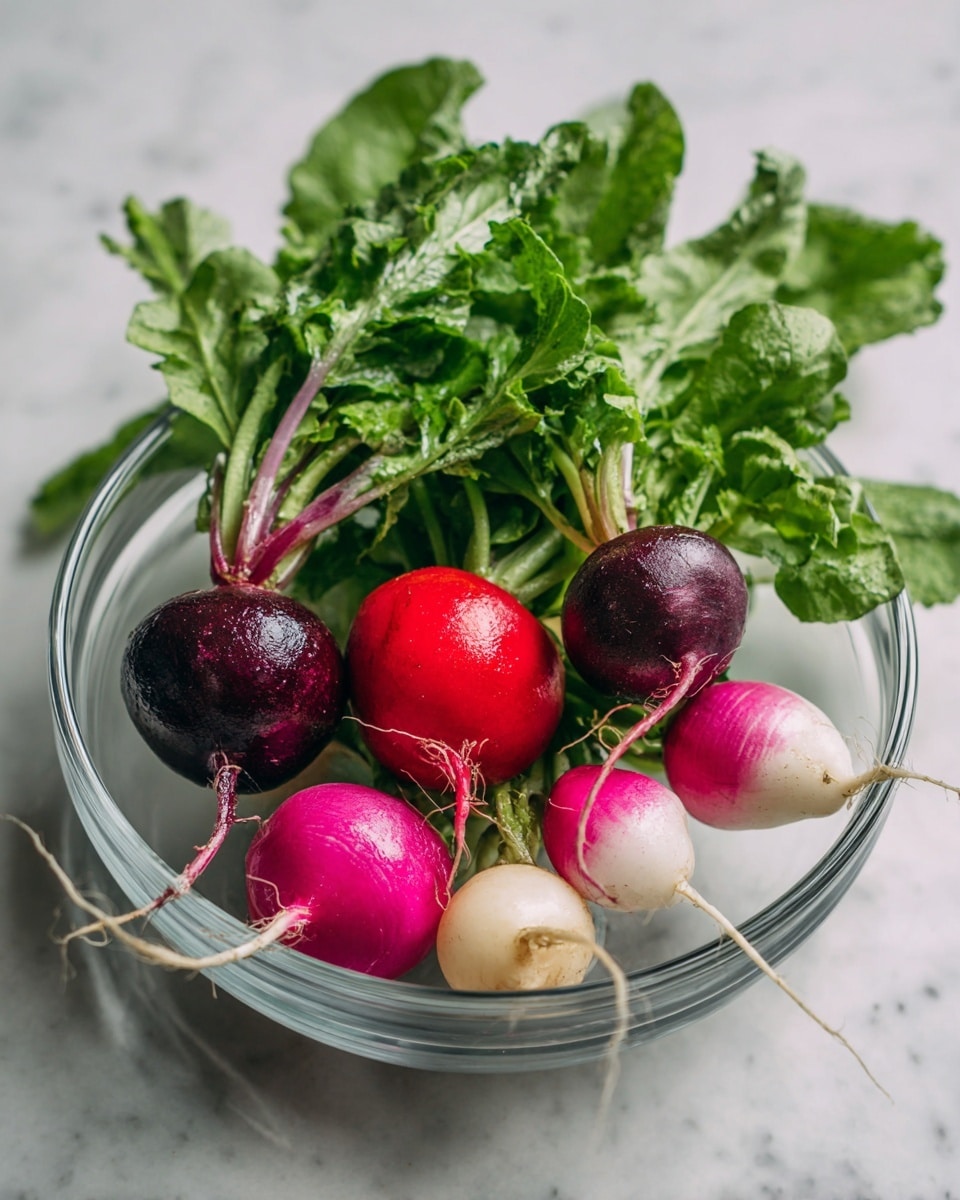 A clear glass bowl filled with fresh radishes of different colors sits on a white marbled surface. The bowl shows eight radishes in total, including bright red, deep purple, light pink, and white radishes with long thin roots. The radishes have fresh green leaves that spread mostly on the right side of the bowl, adding texture and a mix of light and dark green shades. The shiny, smooth radishes contrast with the leafy tops, making the colors and textures stand out clearly. Photo taken with an iphone --ar 4:5 --v 7