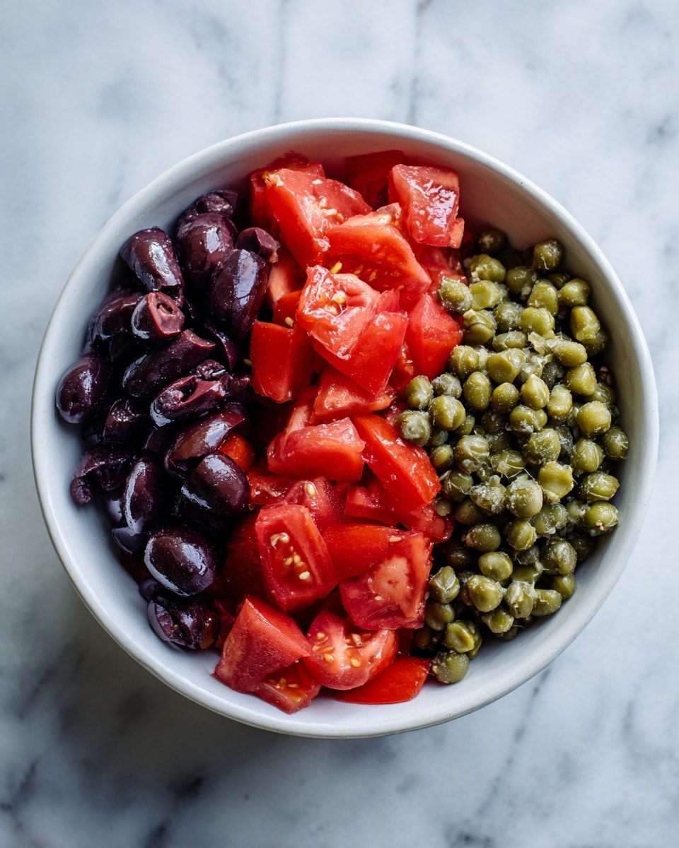 A white bowl shows three separate layers of food on a white marbled surface. The bottom left layer has bright red tomato pieces, cut into medium-sized chunks with a smooth and shiny texture. The top left layer has dark purple chopped olives, roughly chopped with some small bits, showing a moist, slightly rough texture. The right layer contains small round green capers, tightly packed with a smooth, glossy surface. The layers are arranged side by side without mixing. Photo taken with an iphone --ar 4:5 --v 7