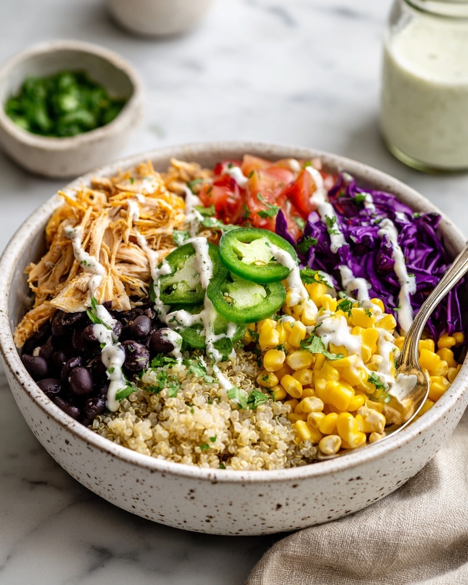 A white bowl filled with multiple colorful layers presents a fresh dish. At the bottom is a layer of light beige quinoa mixed with small pieces of red onion and tomato. On top of the quinoa, there is bright yellow corn mixed with small diced tomato pieces on one side, shredded orange chicken on another, and a portion of black beans on a third side. Above these, slices of green jalapeno peppers and pieces of light green avocado are scattered. Thin strands of purple cabbage rest on top, drizzled with white creamy dressing. A silver spoon is partially inside the bowl, among the quinoa. The bowl sits on a white marbled surface with small specks of green herbs scattered around. photo taken with an iphone --ar 4:5 --v 7
