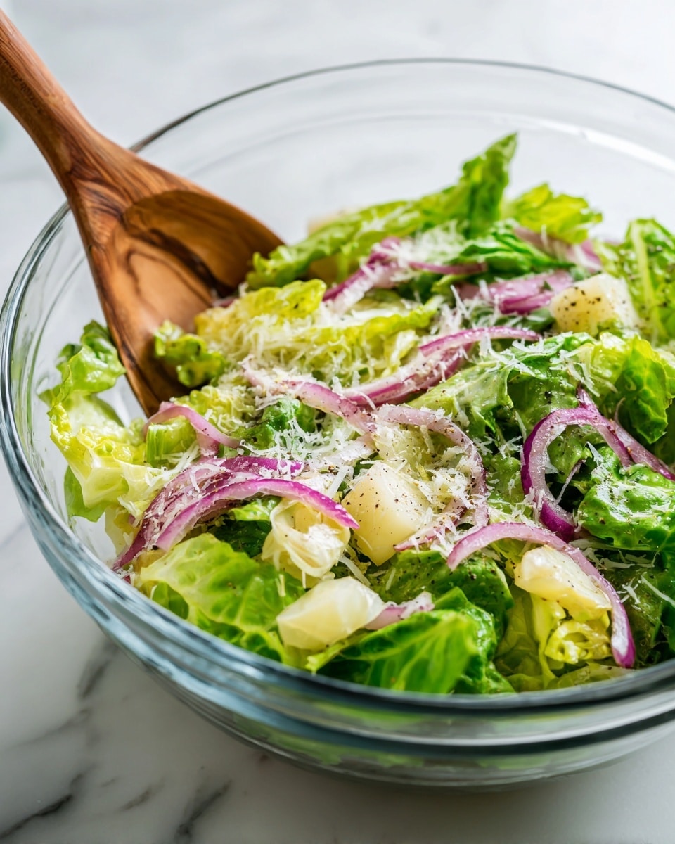 A clear glass bowl filled with a fresh salad showing three main layers: bright green leafy lettuce pieces at the bottom, topped with thin purple onion slices and small chunks of pale yellow fruit or vegetable, sprinkled with fine white grated cheese and light black pepper seasoning all over. A wooden fork is partially immersed on the left side, stirring the salad. The bowl is placed on a white marbled surface. photo taken with an iphone --ar 4:5 --v 7