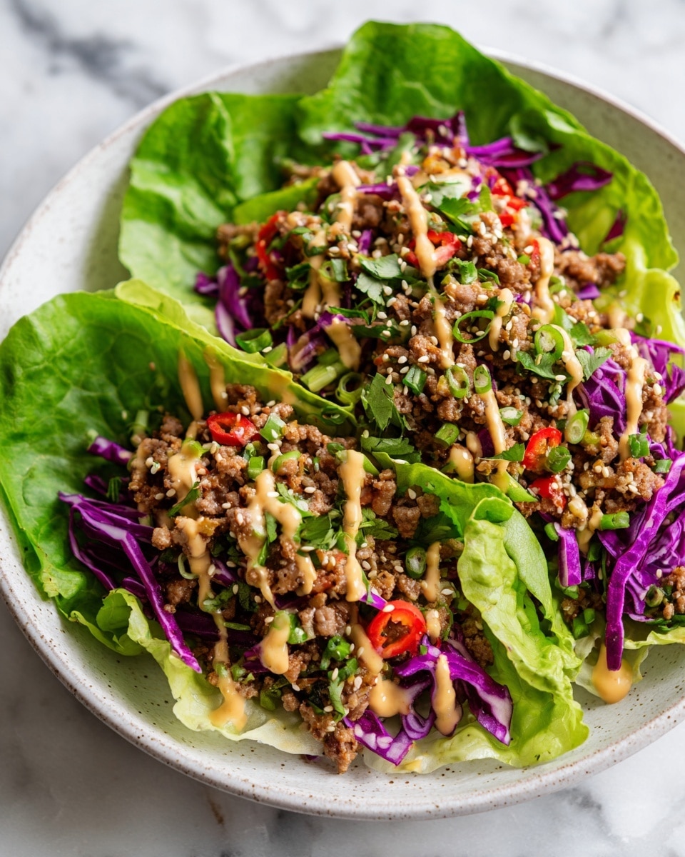 This image shows six small wraps made from bright green lettuce leaves spread out on a white marbled surface. Each lettuce leaf holds a layer of brown cooked ground filling mixed with small red and green vegetable pieces, topped with thin strands of purple cabbage and drizzled with a light tan creamy sauce. On the right side, there is a small white bowl filled with a light tan sauce sprinkled with sesame seeds, next to two lemon wedges and a striped white and gray cloth. The colors in the image contrast well with the white marbled background, showing fresh and vibrant ingredients. Photo taken with an iphone --ar 4:5 --v 7