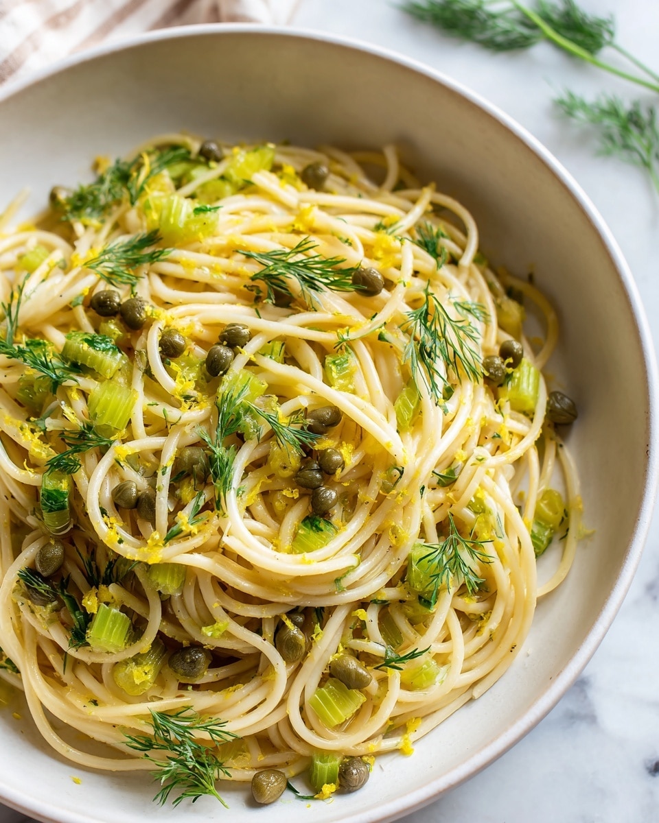 This image shows a white bowl filled with a simple pasta dish. The pasta is light yellow and looks soft, mixed with pieces of white and slightly green fennel, and small green capers spread around. There are bright green dill sprigs placed on top as garnish. The bowl is placed on a white marbled surface with a plain light gray background. The focus is on the pasta close up, showing the detail in the herbs and ingredients, while the edges softly blur. Photo taken with an iphone --ar 4:5 --v 7