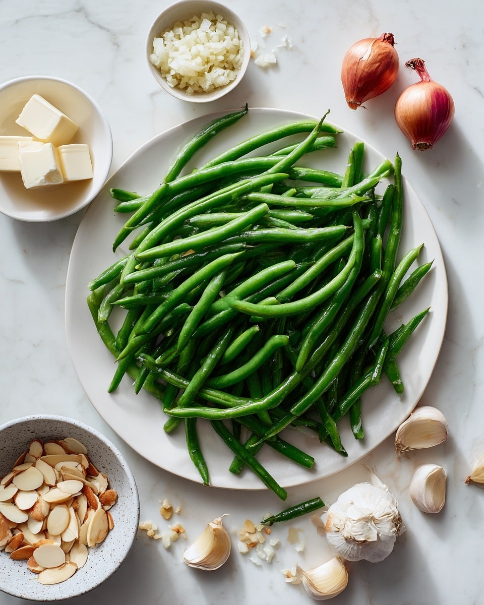 A large white plate holds many fresh green beans spread across it, some spilling over the edges onto a white marbled surface. On the plate towards the top right are two small red shallots. To the right of the plate, a small white bowl contains finely chopped shallots. Near the center of the plate, next to the shallots, is a gray speckled bowl filled with sliced almonds, some almond slices scattered around it. Below the plate, two cloves of garlic rest on the white marbled texture. To the left side of the image, a small white dish holds two cubes of butter. The overall scene shows natural textures and fresh ingredients layered simply on the white plate and white marbled surface, photo taken with an iphone --ar 4:5 --v 7