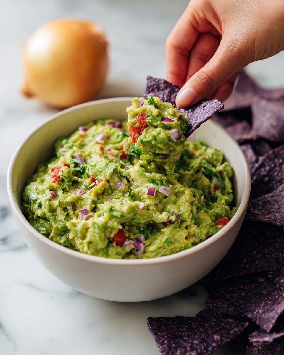 A clear glass bowl filled with thick, chunky green guacamole that has a mix of light and darker green and some pale yellow parts, showing mashed avocado pieces. A woman's hand is holding a silver fork inside the bowl, mixing the guacamole. The bowl is placed on a white marbled surface. photo taken with an iphone --ar 4:5 --v 7