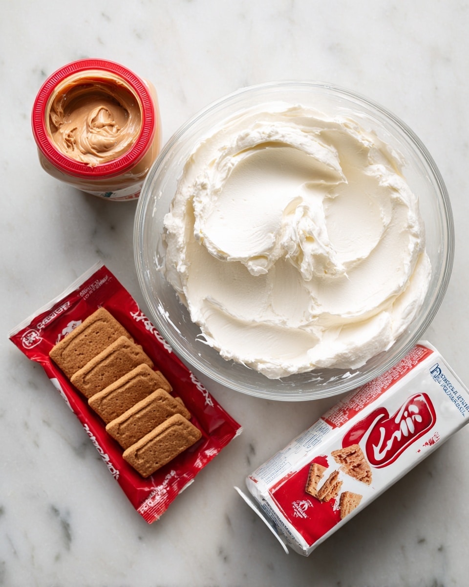 A clear glass bowl filled with thick, white cream cheese sits near the top right, next to a red and white carton of heavy cream placed at an angle below it on a white marbled surface. On the left side, near the top corner, is a jar of Biscoff spread with a red lid and beige spread visible inside. Below the jar lies a red package of Biscoff cookies, containing six rectangular cookies, facing forward. Each item is spaced evenly on the clean white marbled background, making the colors of the packaging and cream cheese stand out clearly photo taken with an iphone --ar 4:5 --v 7