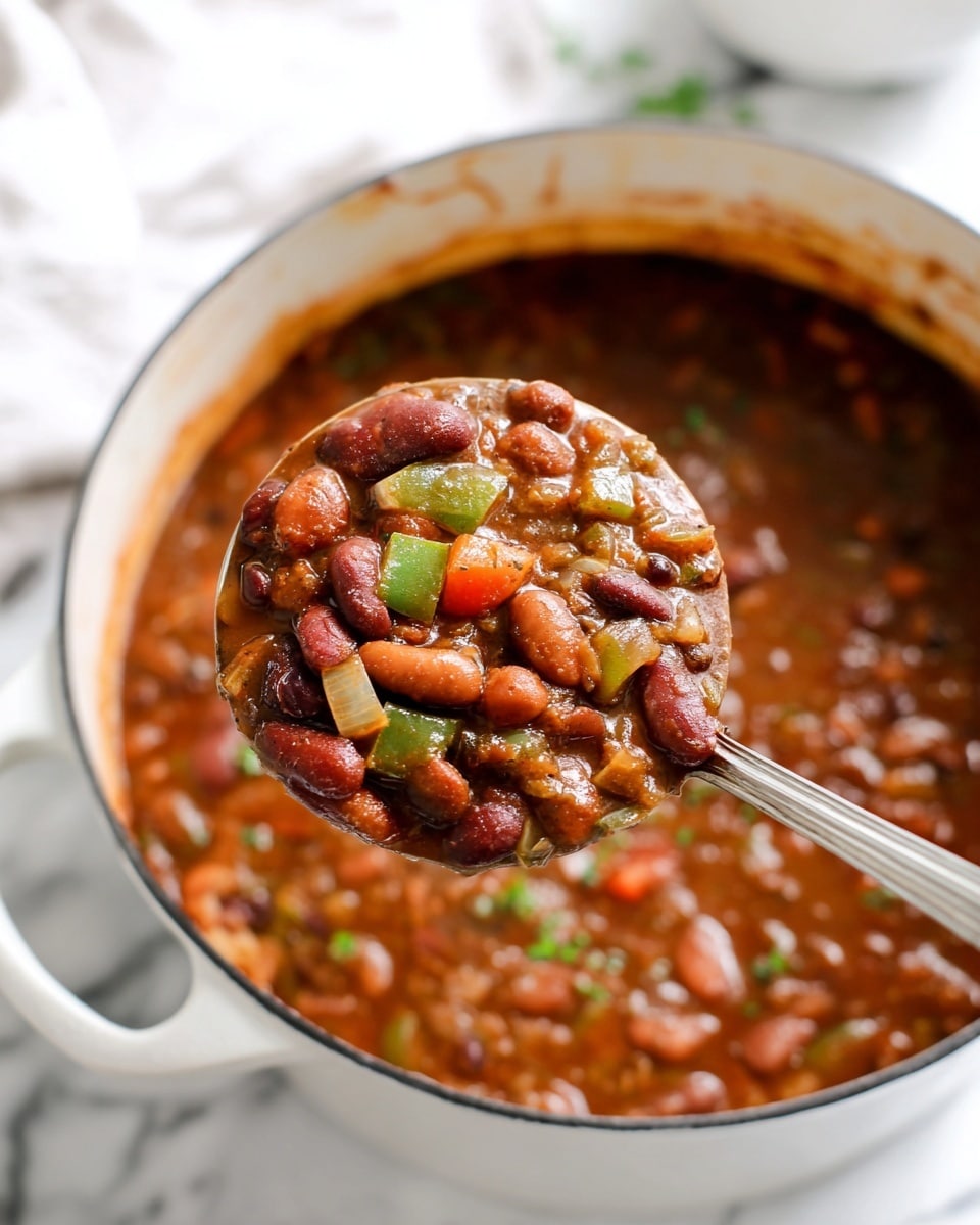 The image shows a white pot filled with a thick bean stew made of different color beans like red, white, and light brown, with chunks of green bell pepper, onions, and diced tomatoes. A large silver ladle is lifting a scoop of the stew, revealing a dense mix of beans and vegetables in a dark reddish-brown sauce. The pot sits on a white marbled surface, and the background is softly blurred with hints of more white bowls. Photo taken with an iphone --ar 4:5 --v 7