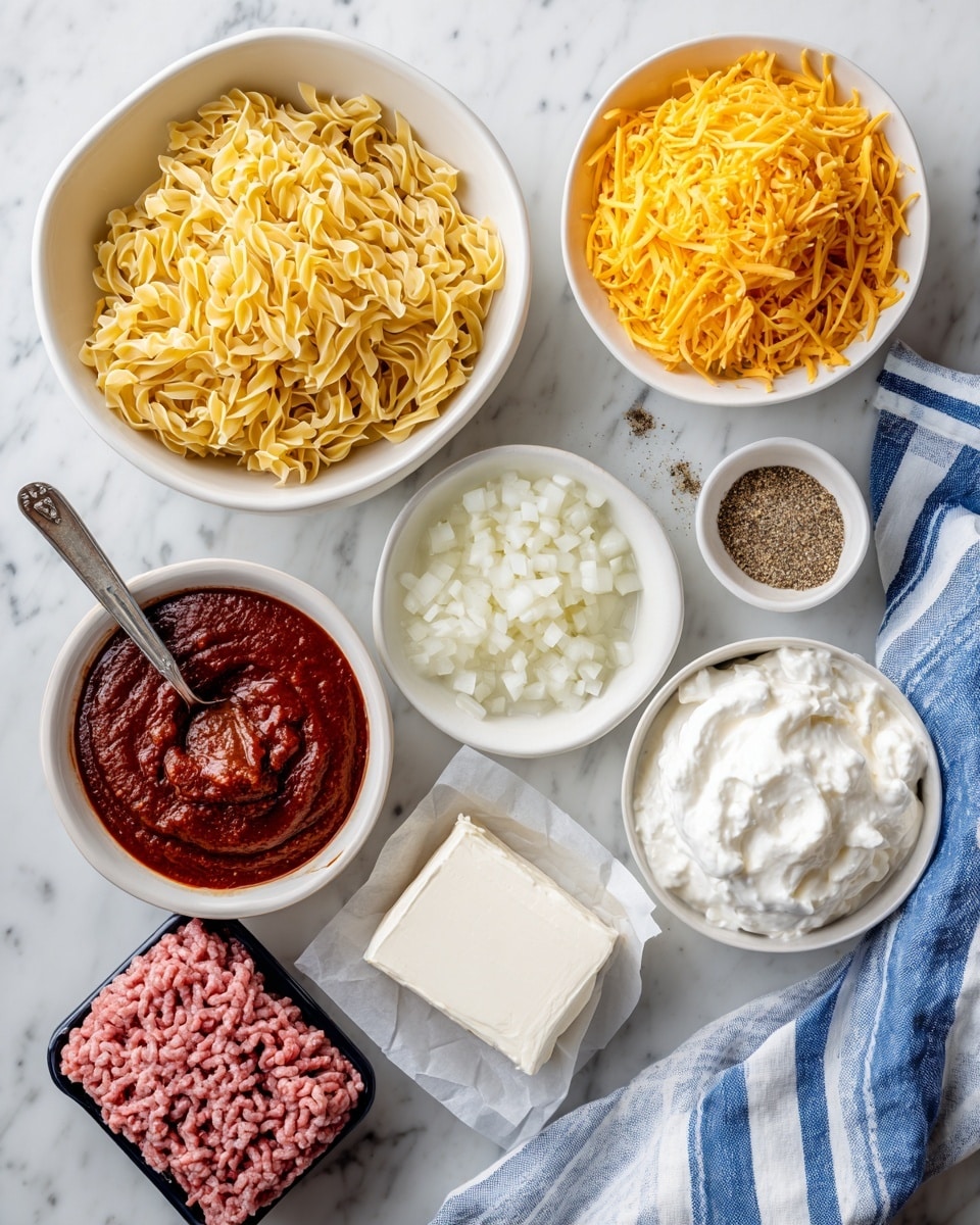 A top-down view of several white bowls and containers on a white marbled surface holding ingredients for a dish: a large white bowl filled with golden yellow egg noodles, another white bowl full of shredded orange cheese, a small white bowl with deep red pasta sauce and a silver spoon resting inside, a white bowl with chopped white onions, a block of white cream cheese on a piece of parchment paper, a small white bowl with steak seasoning made of mixed black and brown spices, a black plastic container with raw pink ground beef, and a white bowl with smooth white sour cream. A blue and white striped cloth is partially visible at the bottom right, and a woman's hand is not shown but implied outside the frame. photo taken with an iphone --ar 4:5 --v 7