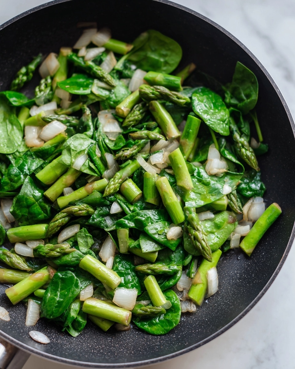 The image shows a close-up view of cooked chopped asparagus pieces mixed with small white onion cubes and bright green spinach leaves. The asparagus segments are thick and tender with a slight shine, while the onions have a soft, slightly translucent look with some light browning. The fresh green spinach leaves add a leafy texture and contrast well with the other ingredients. All the ingredients are spread evenly across the surface of a black non-stick pan, which sits on a white marbled texture background. Photo taken with an iphone --ar 4:5 --v 7