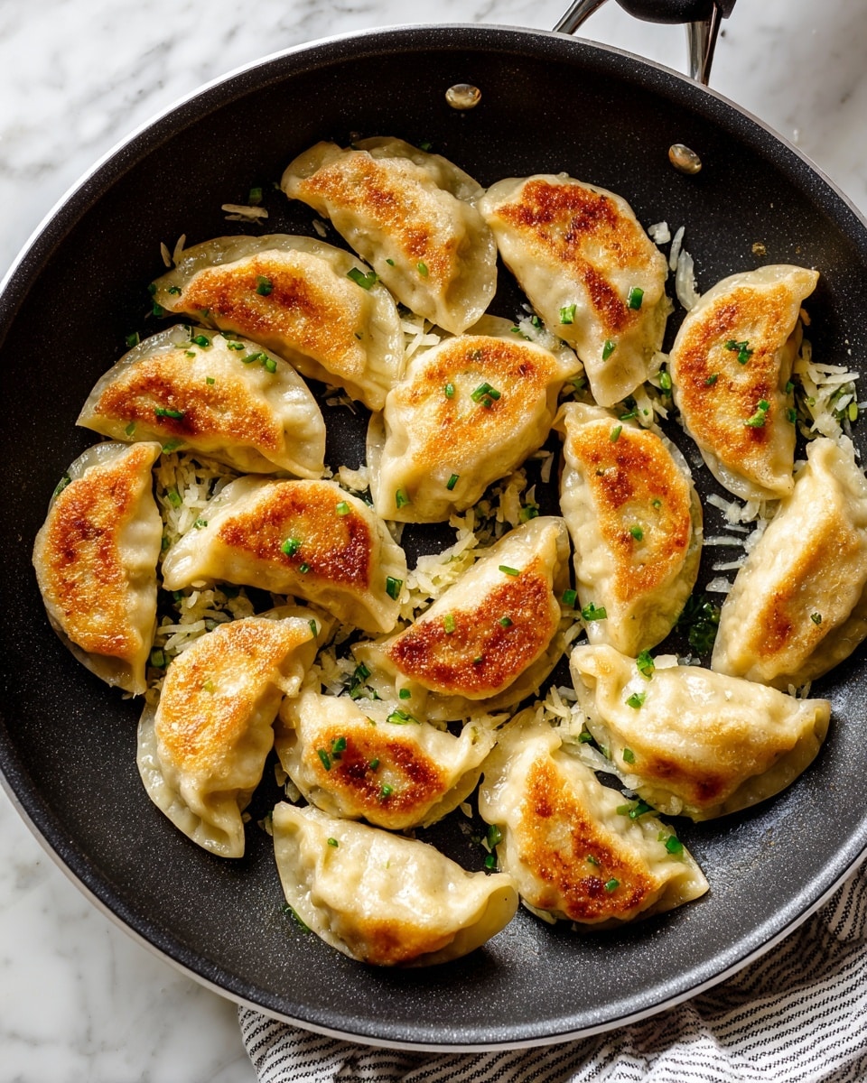 The image shows a frying pan filled with about a dozen golden brown dumplings arranged in an irregular pattern. Each dumpling is slightly curved, with a soft doughy texture that has a crispy, browned side from frying. Small bits of green herbs are sprinkled on top of the dumplings, adding a touch of color. Some shredded pale yellow pieces, likely garlic or ginger, are scattered among the dumplings inside the pan. The frying pan is sitting on a white marbled surface with a striped cloth partially visible under it. Photo taken with an iphone --ar 4:5 --v 7