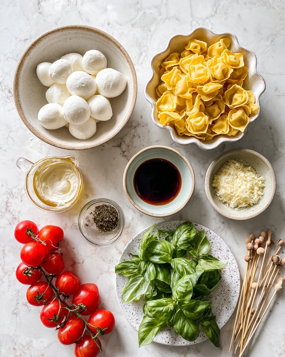 The image shows a top view of various fresh ingredients arranged on a white marbled surface. On the top right, a white bowl is filled with yellow tortellini pasta. Below it, a ceramic bowl with a scalloped edge holds several white balls of mozzarella cheese. To the center right, two small ceramic bowls contain grated cheese and a mix of minced garlic with herbs. Near the center, a clear measuring cup holds brown olive oil, next to it a small white ceramic bowl contains dark balsamic vinegar. A beige bowl with a smooth, creamy white sauce is positioned on the left. Below that, a white speckled plate is piled with fresh green basil leaves. Bright red cherry tomatoes are on the vine, both on the top left and bottom right, scattered with wooden skewers with knotted tops laying between them. photo taken with an iphone --ar 4:5 --v 7