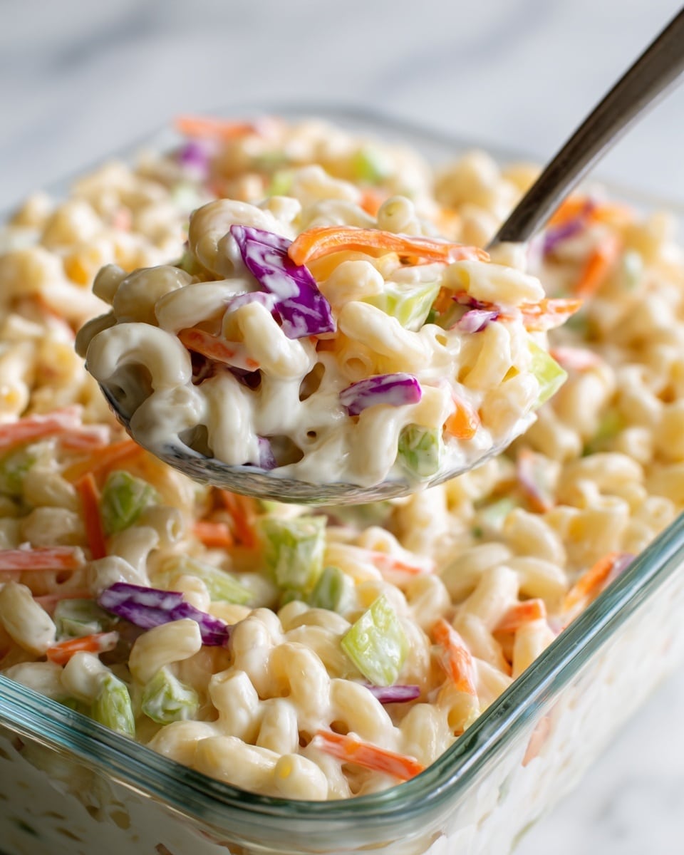 The image shows a white bowl filled with a pasta salad made of curly pasta mixed with thin strips of orange carrots, purple cabbage, white cabbage, and small light beige pieces that appear to be chicken. The ingredients are evenly spread and mixed throughout the bowl, giving a colorful and fresh look with a mix of soft pasta and crunchy vegetables on a white marbled surface. In the background, there is a white plate and a knife with a black handle. photo taken with an iphone --ar 4:5 --v 7